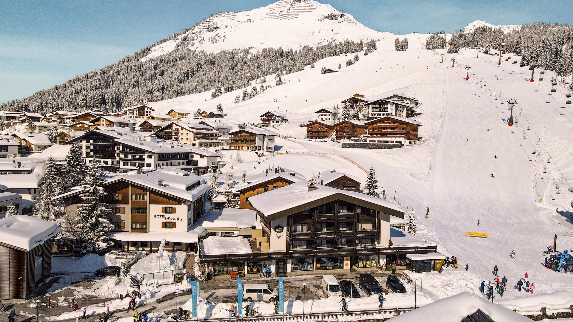 Schneebedecktes Skiresort mit Berghotel und Skifahrern am Hang