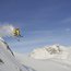 Skifahrer springt von steilem schneebedecktem Berg bei klarem Himmel